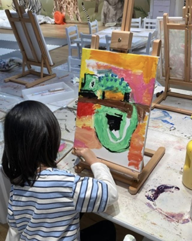 Child painting a chameleon on an easel