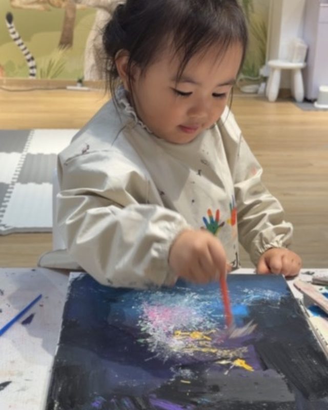 Toddler painting a galaxy canvas