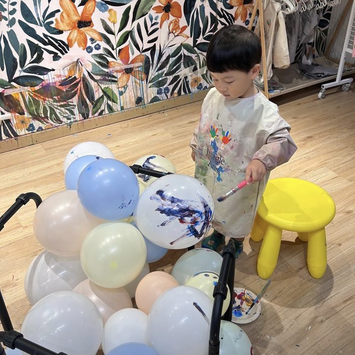 Toddler painting balloons with a brush