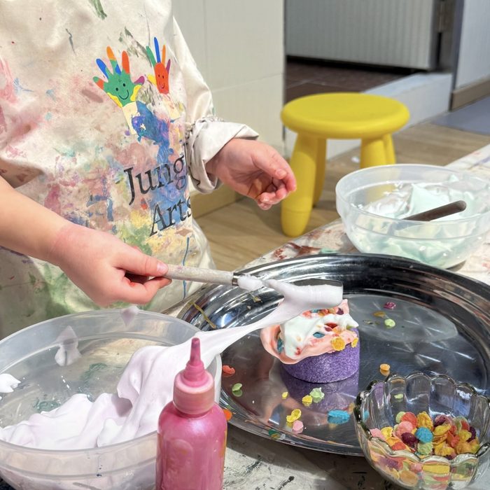 Child decorating a sponge cake with foam and sprinkles