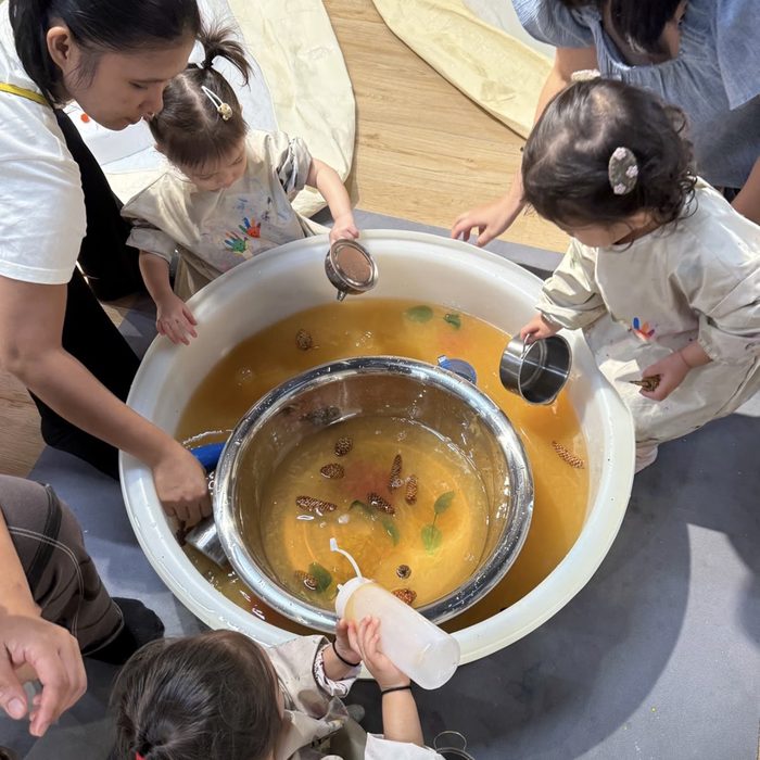 Toddlers pouring and scooping in a water play tub