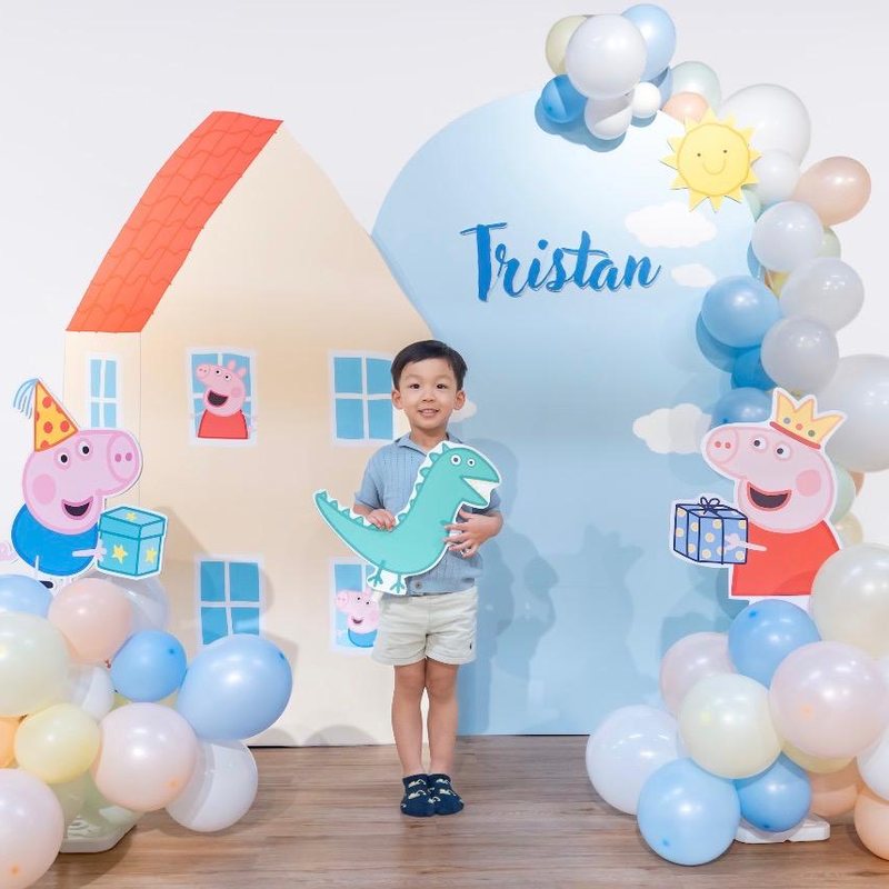 Peppa Pig party backdrop with house, balloons and character cut-outs
