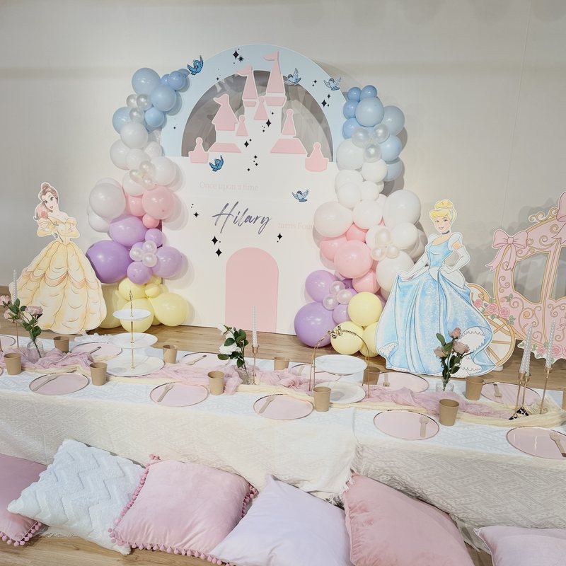 Princess party with castle backdrop, balloons and a low table with cushions